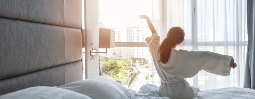 Woman sitting in bed looking at the sunrise